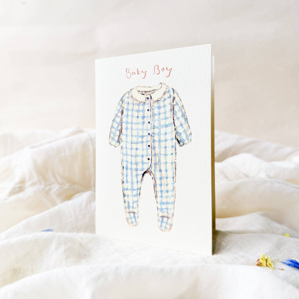 Greeting card with a blue checkered baby onesie illustration on a white background