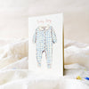 Greeting card with a blue checkered baby onesie illustration on a white background