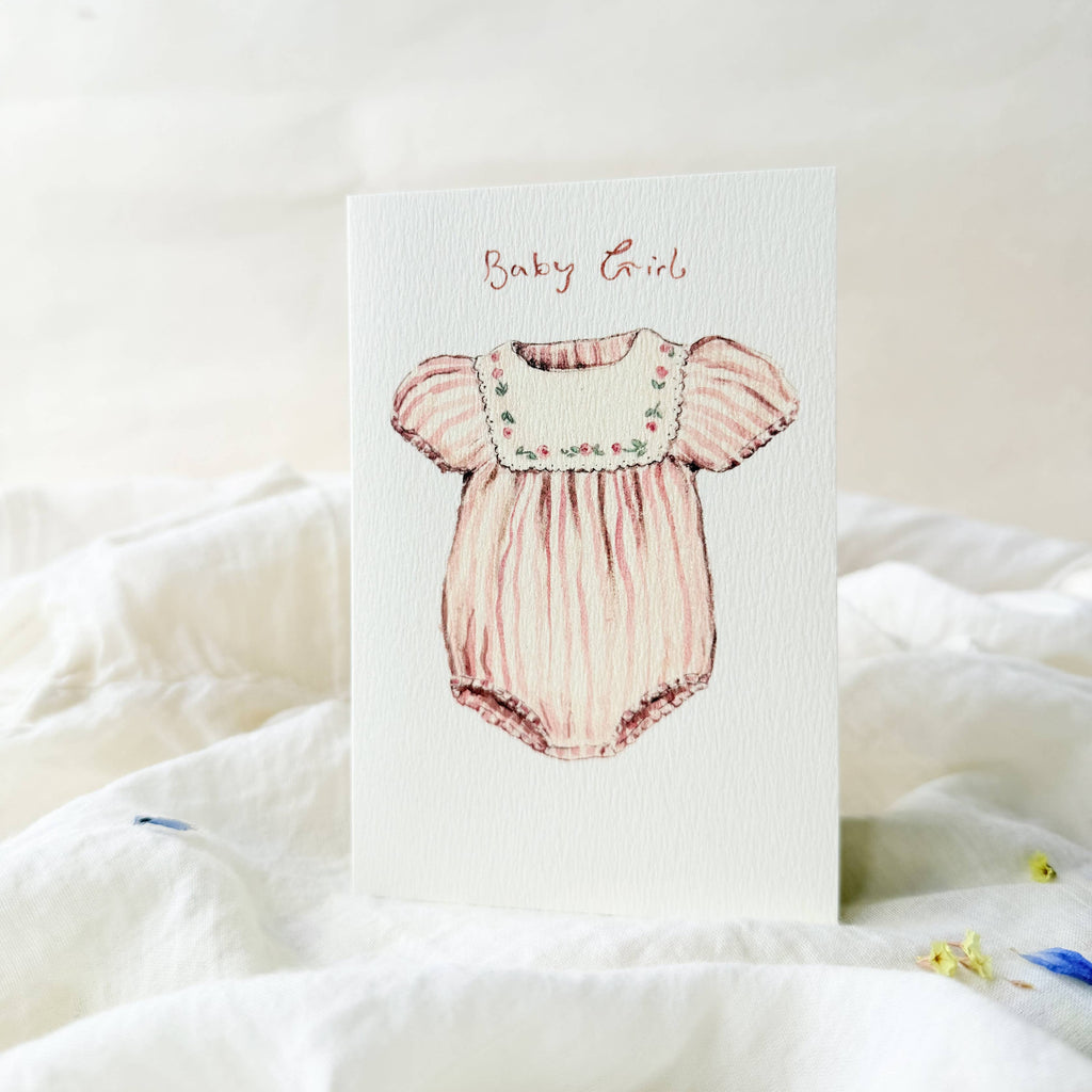 Card with a pink baby romper illustration and 'Baby Girl' text on a soft white background.