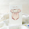 Card with a pink baby romper illustration and 'Baby Girl' text on a soft white background.