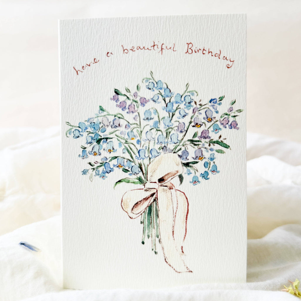 Greeting card with blue flowers and a pink ribbon on a white background