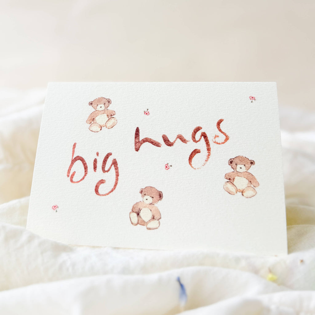 Card with 'big hugs' text and teddy bear illustrations on a soft white background