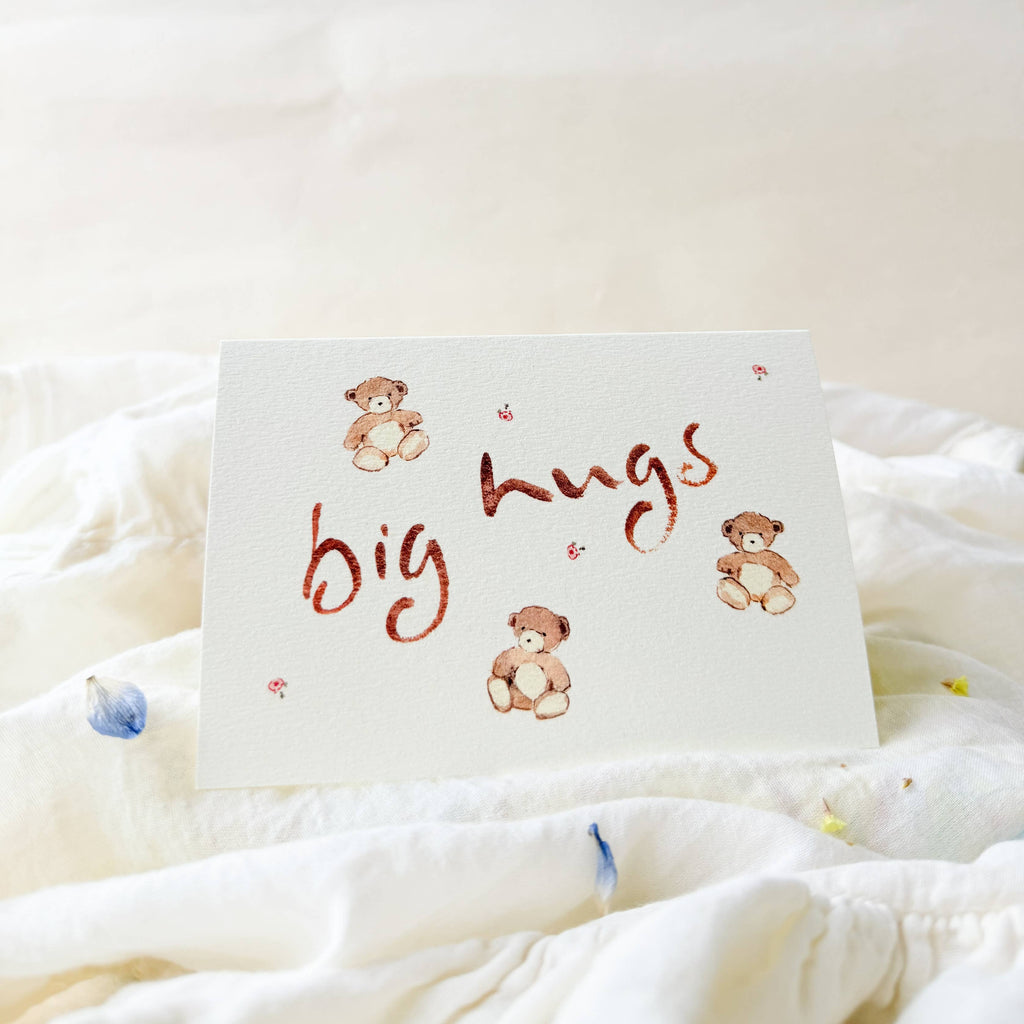 Card with 'big hugs' text and teddy bear illustrations on a soft white background