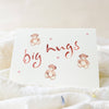 Card with 'big hugs' text and teddy bear illustrations on a soft white background