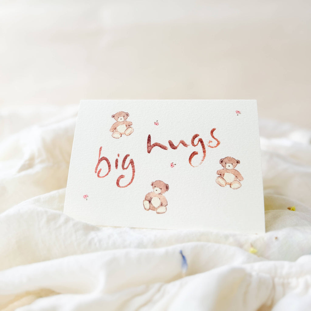 Card with 'big hugs' text and teddy bear illustrations on a soft white background