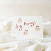 Card with 'big hugs' text and teddy bear illustrations on a soft white background