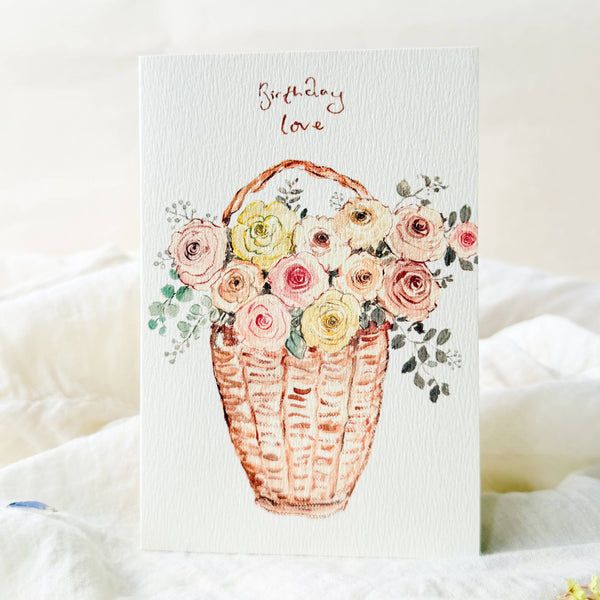 Greeting card with a floral basket illustration and 'Birthday Love' text on a white background.
