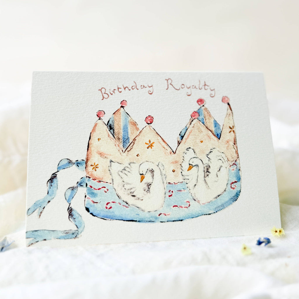 Greeting card with two swans wearing crowns and the text 'Birthday Royalty' on a white background.