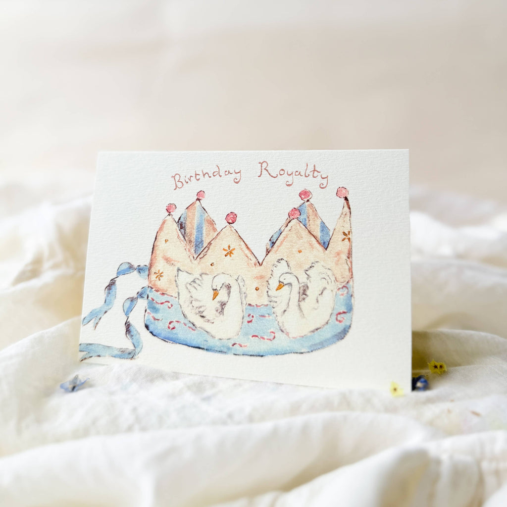 Greeting card with a crown design and 'Birthday Royalty' text on a soft white background.