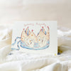 Greeting card with a crown design and 'Birthday Royalty' text on a soft white background.