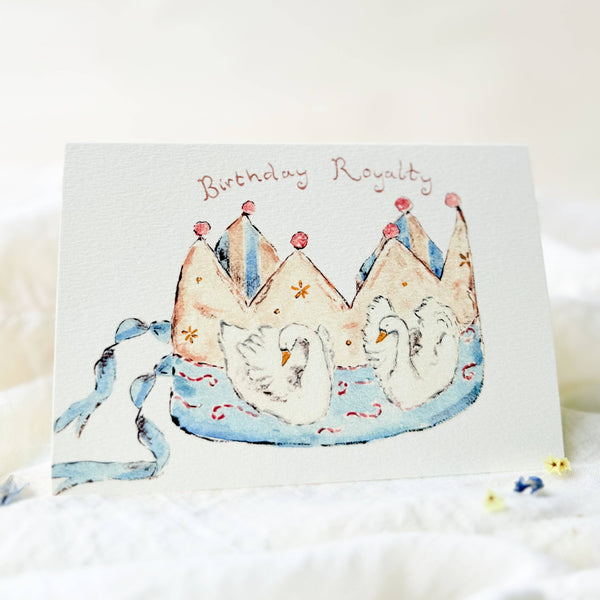 Greeting card with two swans wearing crowns and the text 'Birthday Royalty' on a white background.