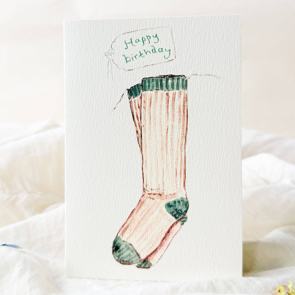 Birthday card with a sock illustration and 'Happy Birthday' text on a white background.