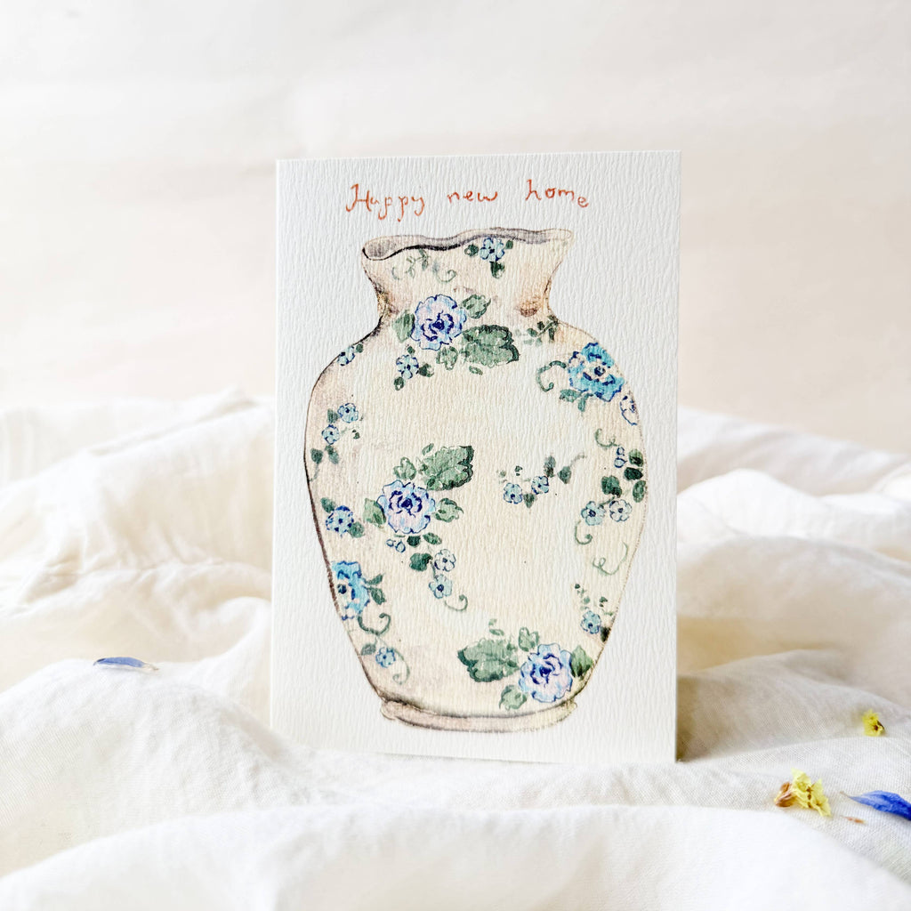 Card with floral vase design and 'Happy New Home' text on a soft white background