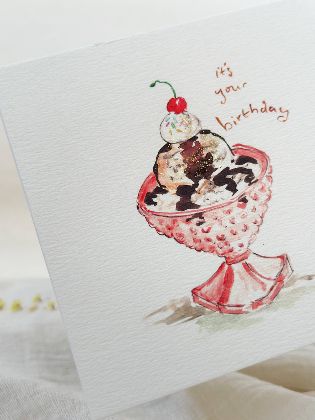 Greeting card with a illustration of a sundae and 'It's your birthday' text on a white background.