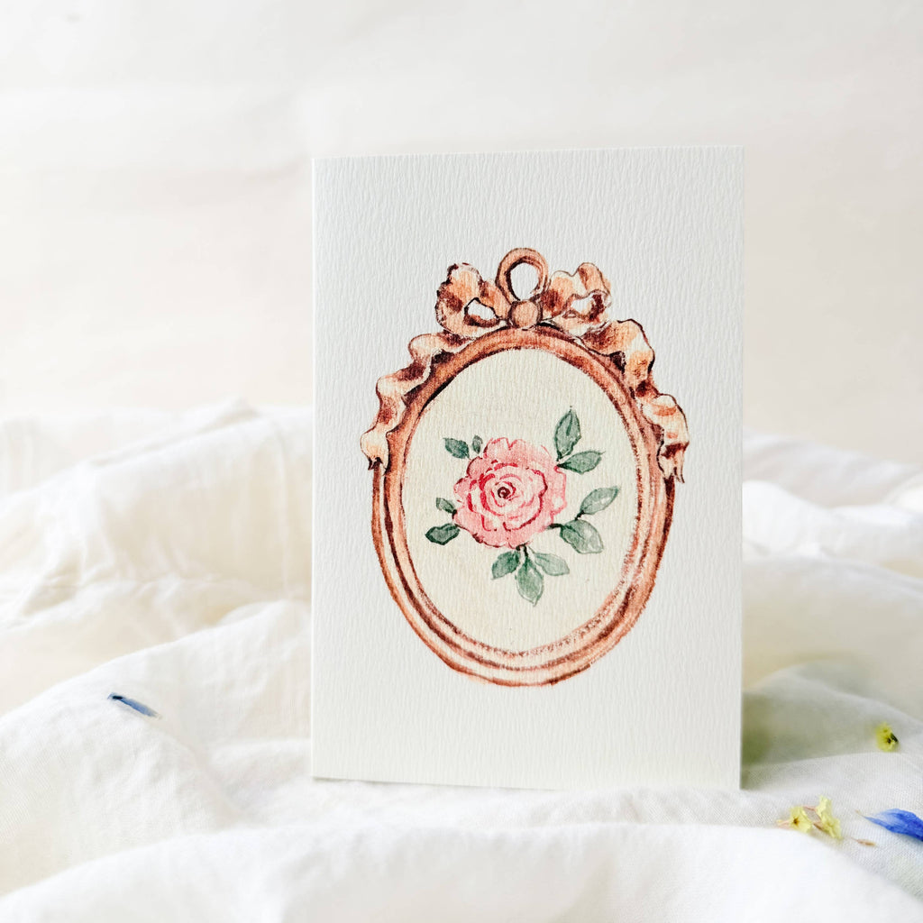 Card with a decorative rose gold frame and floral design on a white background