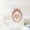 Card with a decorative rose gold frame and floral design on a white background