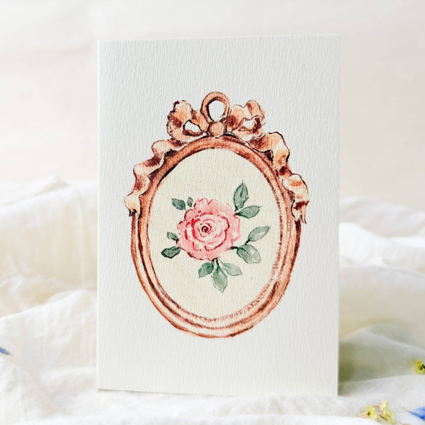 Decorative card with a pink rose and floral frame on a white background
