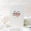 Card with baby booties illustration and 'tiny toes!' text on a soft white background