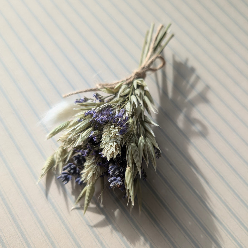 Bouquet of dried lavender and green herbs tied with twine on a striped surface