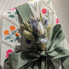 Floral-patterned fabric with a green ribbon and dried flowers
