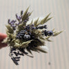 Bouquet of dried lavender and greenery held by a hand against a neutral background