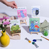 Set of small paintings with cartoon characters on a table with art supplies.