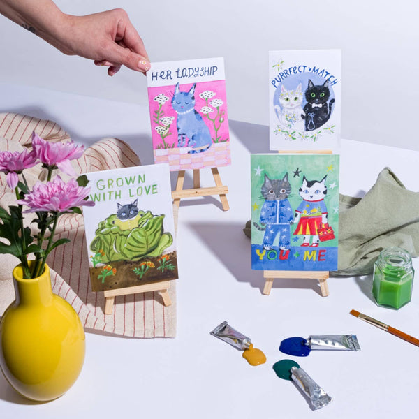 Set of small paintings with cartoon characters on a table with art supplies.