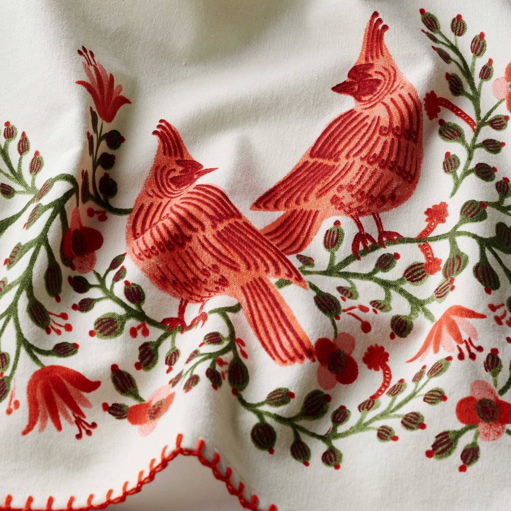 Embroidered design of red birds and flowers on a white fabric background