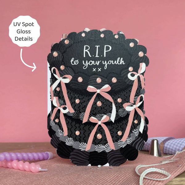 Decorative cake with 'R.I.P. to your youth' text on a pink background
