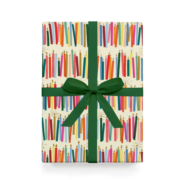Gift box with colorful book pattern and green ribbon on a white background