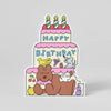 Sticker of a birthday cake with candles and a bear holding a cake on a gray background