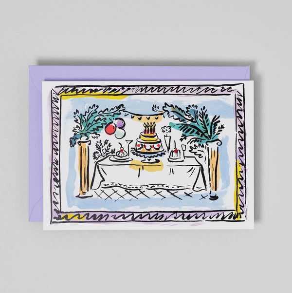 Greeting card with a drawing of a birthday cake on a table, framed by decorative elements on a gray background.