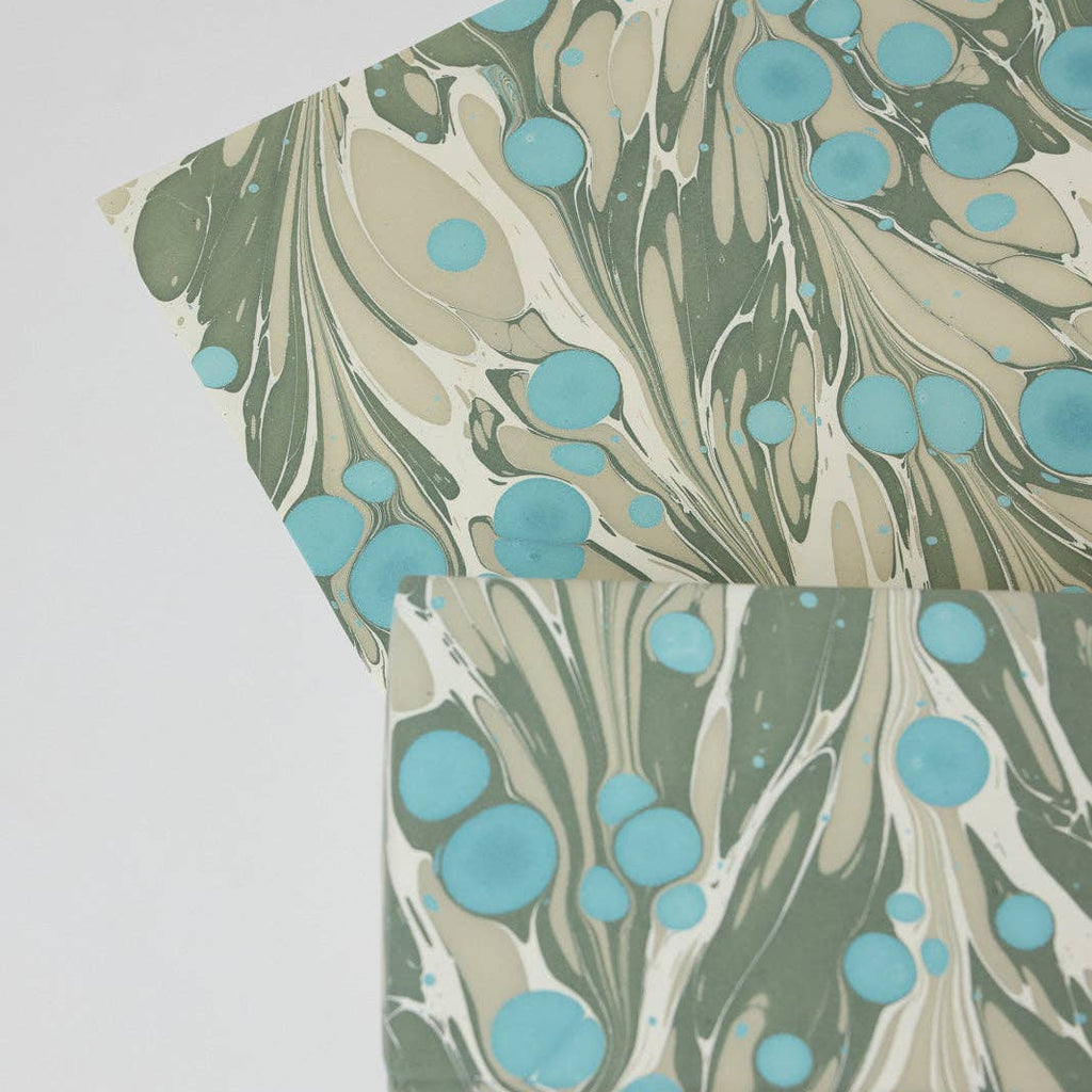 Marbled paper with green and blue patterns on a white background