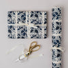 Floral-patterned gift wrap with scissors on a light gray background