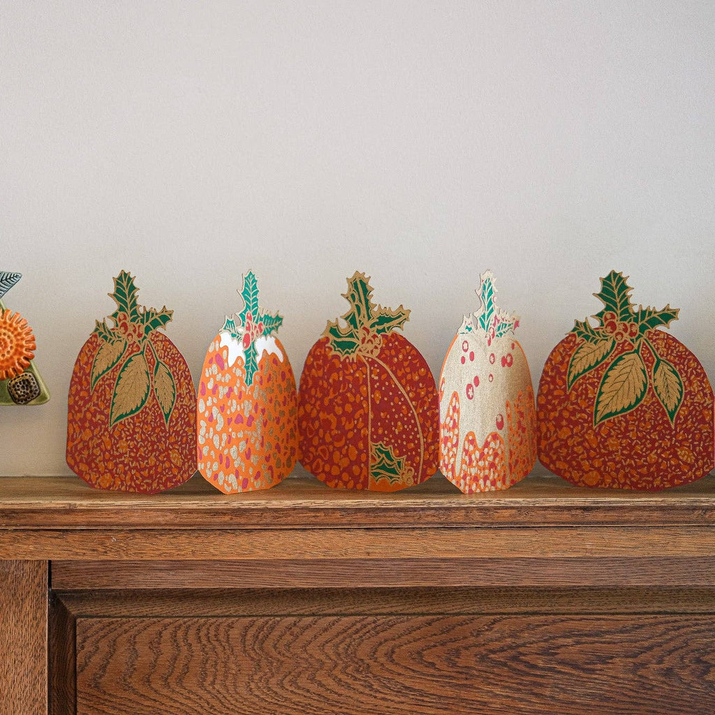 Decorative items including a colorful tree and pumpkins on a wooden surface.