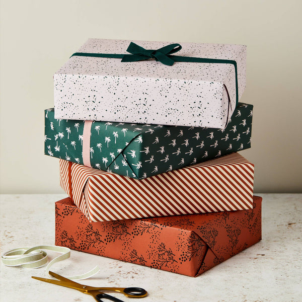 Stack of gift boxes with different patterns and a ribbon on a light surface.