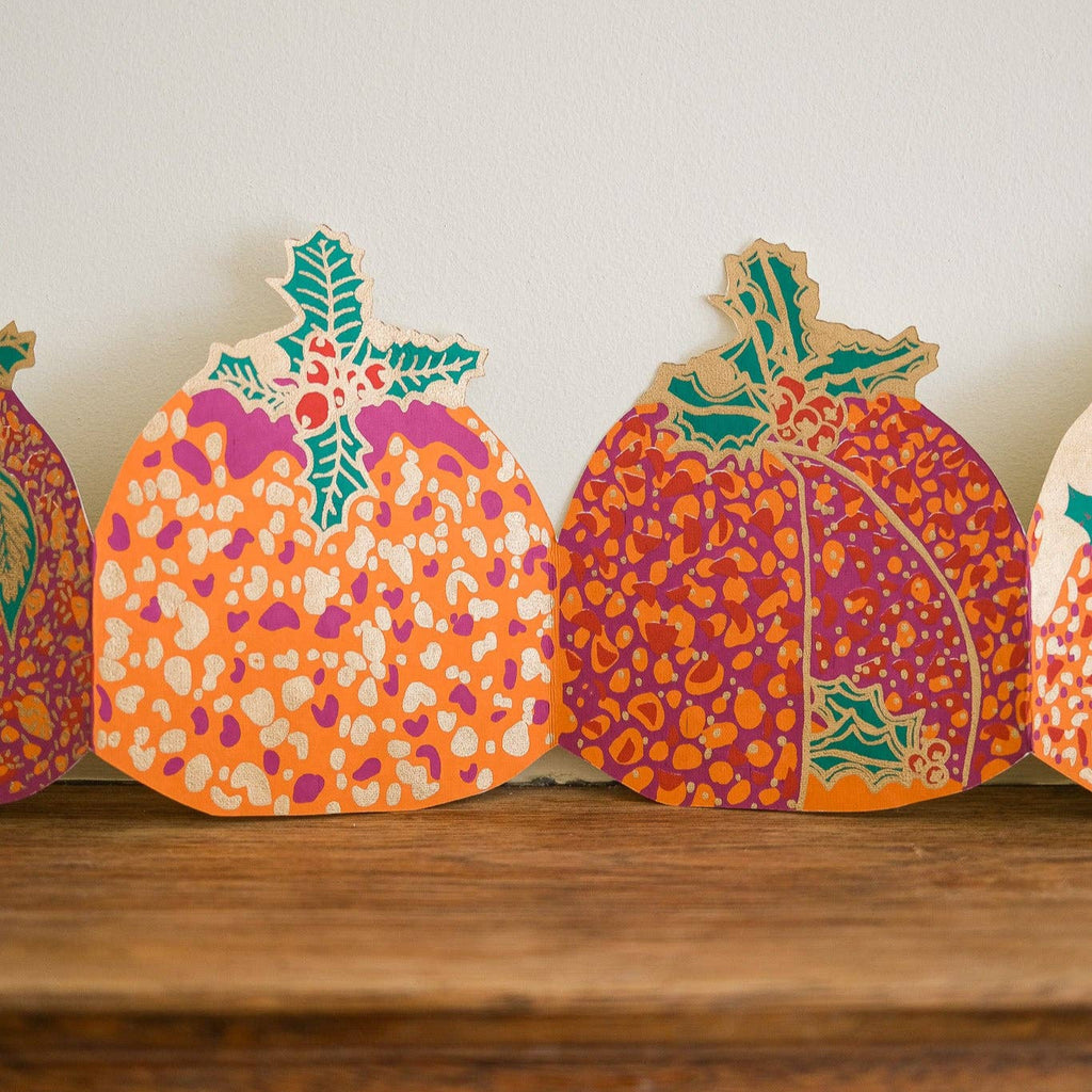 Decorative paper pumpkins with floral patterns on a wooden surface.