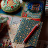 Decorative stationery items including a notebook, pen, and gift box on a colorful surface.