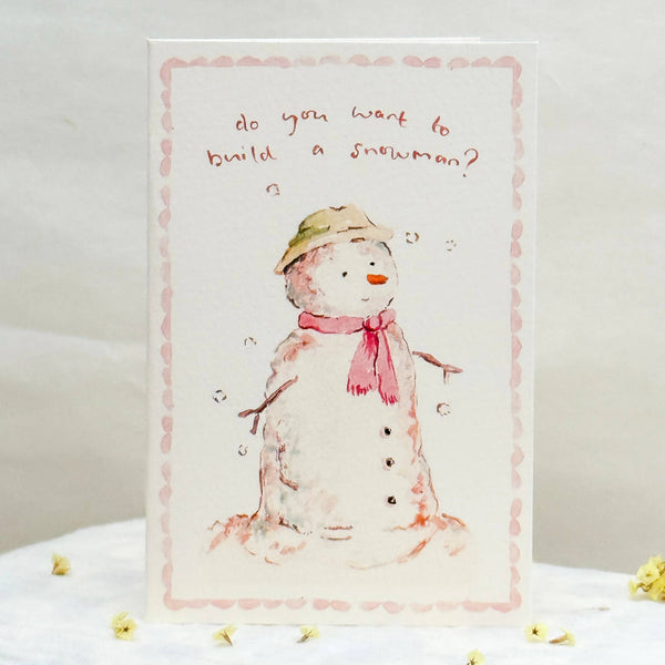 Card with a snowman illustration and text on a white surface