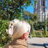 Person with blonde hair and a pink bow standing in front of Notre Dame Cathedral
