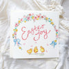 Easter-themed card with chicks, flowers, and 'Easter Joy' text on a white fabric background.