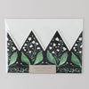 Floral design with green leaves and white flowers on a black background, featuring a beige label.