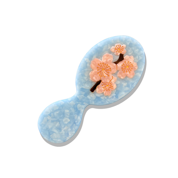 Decorative hairbrush with cherry blossom design on a light blue background