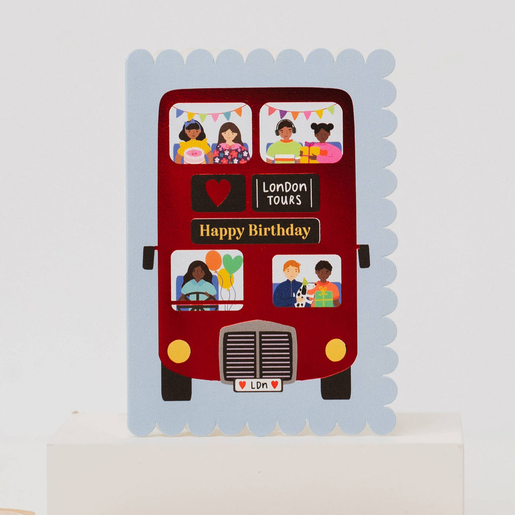 Red bus-shaped birthday card with cut-out windows featuring children's drawings on a white background.