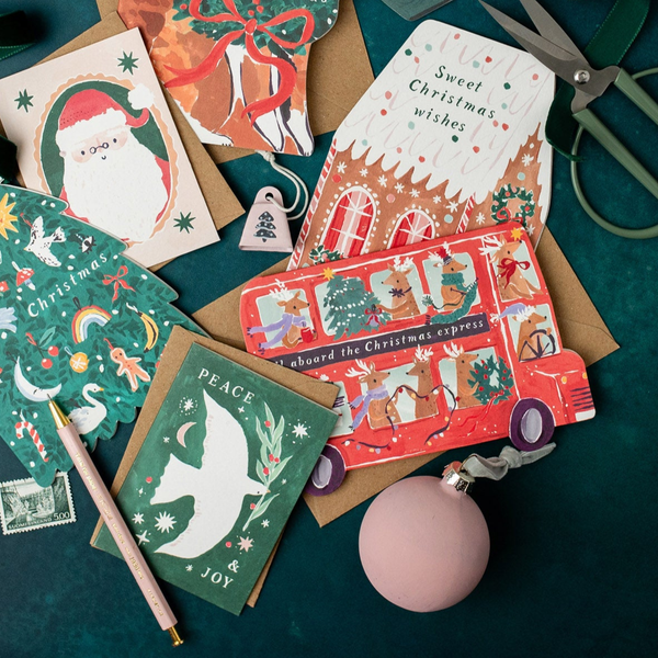 Collection of Christmas-themed greeting cards on a green surface with decorative items.