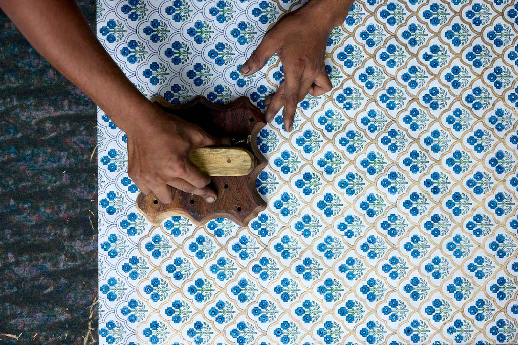 Person using a wooden tool on a blue and white patterned fabric.