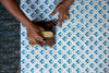 Person using a wooden tool on a blue and white patterned fabric.