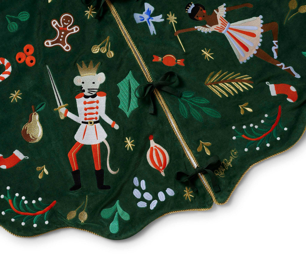 Decorative green Christmas tree skirt with embroidered festive designs on a white background