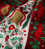 Embroidered fabric with red, green, and gold floral and bird patterns.