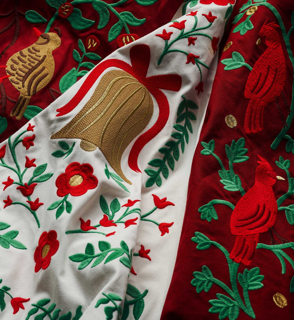 Embroidered fabric with red, green, and gold floral and bird patterns.